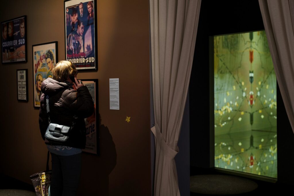 Au coeur de l'exposition Le Petit Prince à Strasbourg, où un groupe de visiteurs et visiteuses observent les objets exposés.