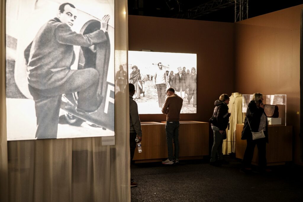 Au coeur de l'exposition Le Petit Prince à Strasbourg, où un groupe de visiteurs et visiteuses observent les objets exposés.